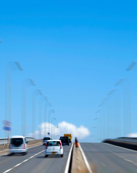 Cars driving on a bridge under a clear blue sky