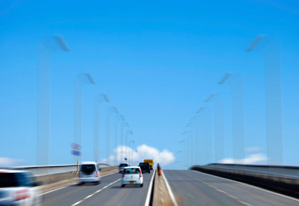 Cars driving on bridge under clear blue sky-img