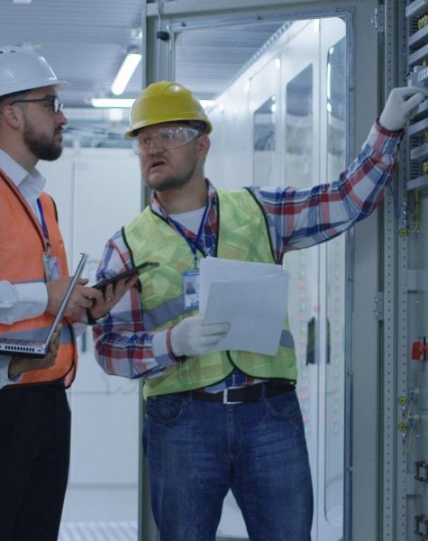 Diverse engineers with papers working in control center between racks
