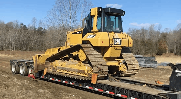 Caterpillar bulldozer loaded on a flatbed trailer at a jobsite