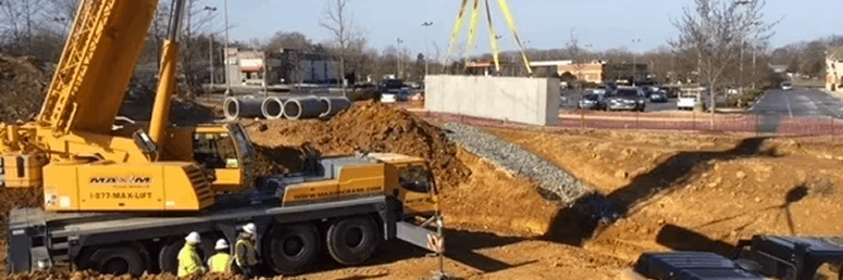 Crane lifting a concrete beam at a construction site with workers below