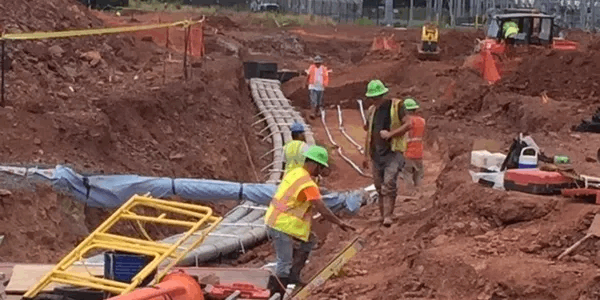 Construction crew installing pipework in an excavated dirt site