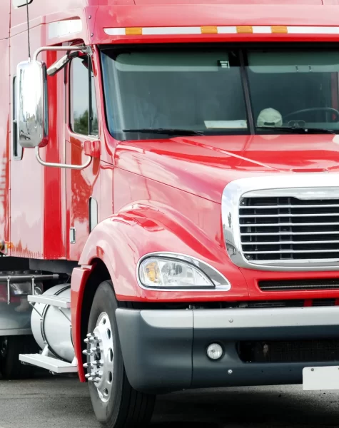 Red semi-truck driving on a road, side view